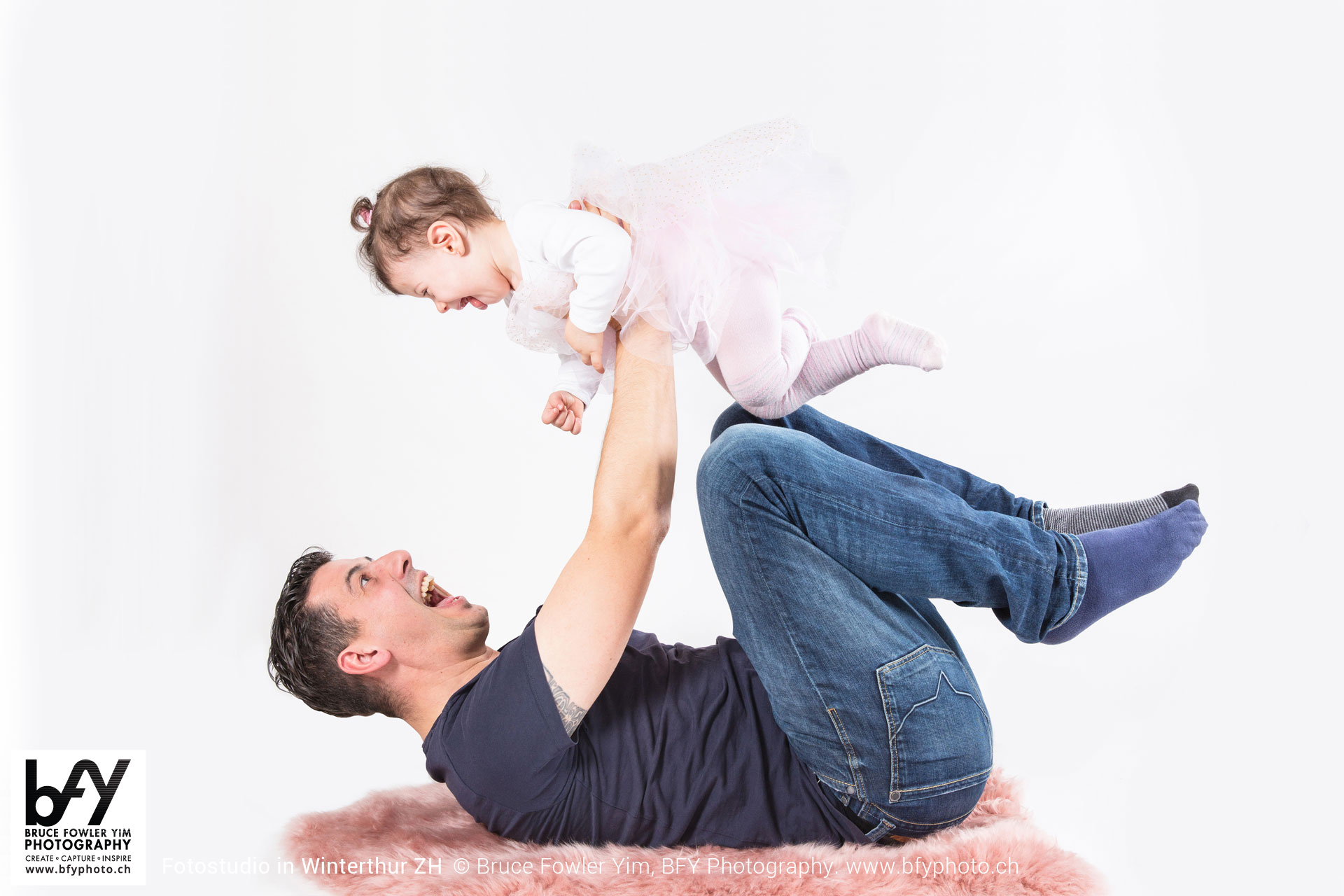 Father holding baby in the air and making him giggle, isolated o