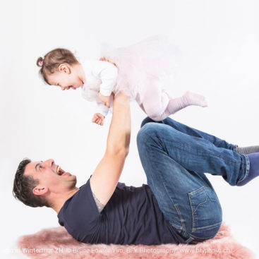 Father holding baby in the air and making her giggle